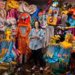 Artist Cheryl Capezzuti stands in the center of many of her puppet creations. She is wearing a 
